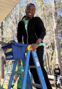 UMW students, like Aloysious Kabonge on the ladder, were onsite performing construction tasks at a housing initiative for families in need of safe, affordable spaces.